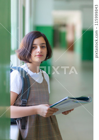 Beautiful girl in the school hallway reading a book Beautiful girl in the school hallway reading a book 115999843