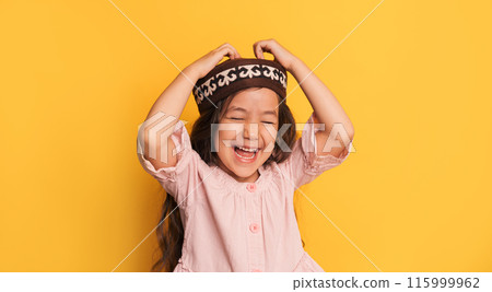 Little girl in a Kazakh skullcap in front of a yellow background Little girl in a Kazakh skullcap in front of a yellow background 115999962