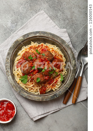 Spaghetti and meatballs with tomato sauce served on rustic plate with cutlery top view, Italian cuisine Spaghetti and meatballs with tomato sauce served on rustic plate with cutlery top view, Italian cuisine 116000543
