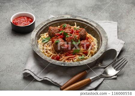 Spaghetti being served with meatballs and tomato sauce in rustic bowl, Italian cuisine Spaghetti being served with meatballs and tomato sauce in rustic bowl, Italian cuisine 116000558