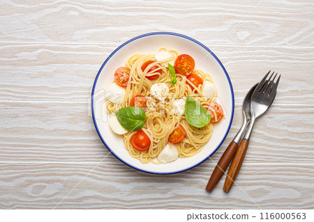 Plate of spaghetti pasta with cherry tomatoes and mozzarella cheese on white background 116000563