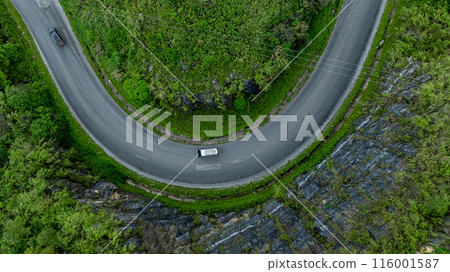 Aerial view road through the green forest on mountain road, Car drive on asphalt road going through green forest, Curved road from above. Aerial view road through the green forest on mountain road, Car drive on asphalt road going through green forest, Curved road from above. 116001587