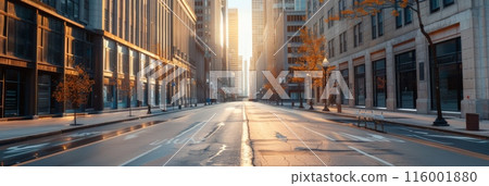 Empty city street during sunrise with tall buildings and reflections, highlighting urban tranquility. 116001880