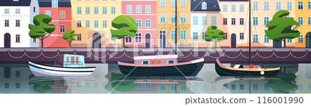 Colorful waterfront scene with boats docked along a canal lined with vibrant buildings and lush trees reflecting in the water 116001990