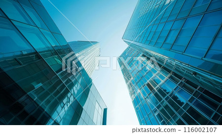 Upward view of skyscrapers with glass facades against a clear sky. Modern urban architecture and business growth concept. 116002107