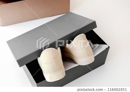 A pair of new beige sneakers in a box.  116002851