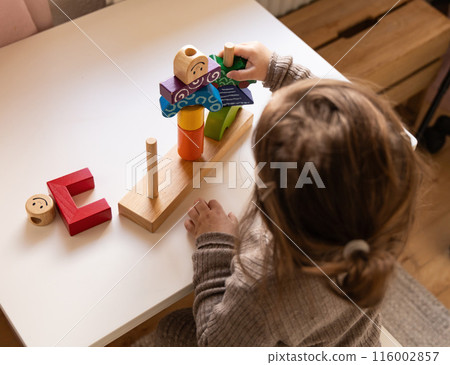 Child playing a fun-filled game of logic with colourful wooden blocks. Child playing a fun-filled game of logic with colourful wooden blocks. 116002857