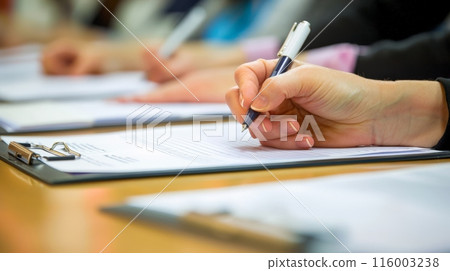 Close-up of hands writing on a clipboard during a business meeting. Business administration and teamwork concept. 116003238