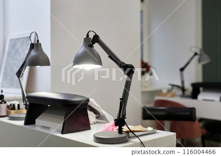 Still life shot of modern nail shop equipment on manicure table in nail salon bright interior. Inside empty beauty studio with white design, copy space 116004466