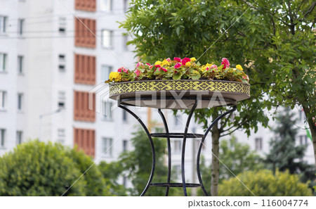 Decorative stone flower vase outdoors with ornamental plants and flowers in public garden Decorative stone flower vase outdoors with ornamental plants and flowers in public garden 116004774