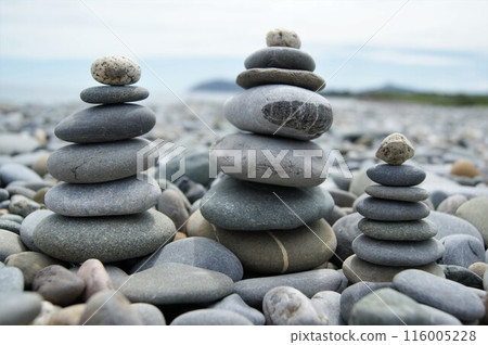 Towers made of pebbles. Three Zen towers on a rocky beach. 116005228