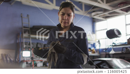 Image of glowing light over biracial woman working in car workshop Image of glowing light over biracial woman working in car workshop 116005425