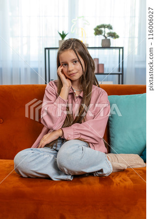 Portrait of happy smiling young girl child kid sitting on home couch 116006027