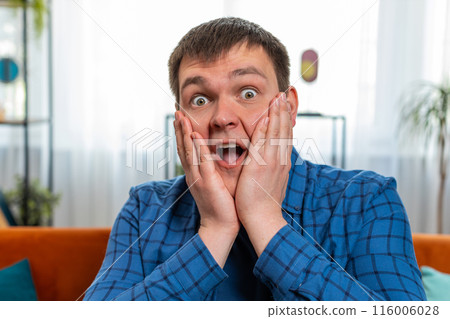 Excited shocked amazed young man surprised looking at camera with big eyes wow emotion good win news 116006028