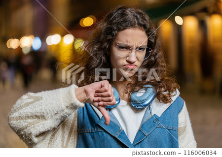 Upset teenage girl child showing thumbs down dislike sign gesture expressing discontent disapproval Upset teenage girl child showing thumbs down dislike sign gesture expressing discontent disapproval 116006034