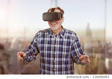 Happy smiling elder man in vr headset. Blurred cityscape background. Happy smiling elder man in vr headset. Blurred cityscape background. 116006065