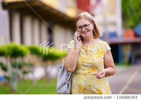 Senior woman with mobile phone on city street 116006365