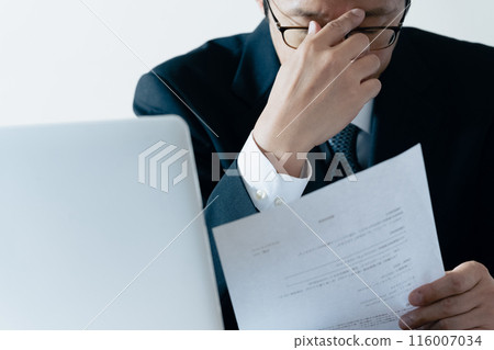 A man in charge of recruitment looking at documents and worrying A man in charge of recruitment looking at documents and worrying 116007034