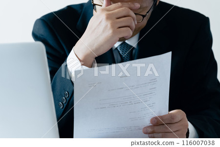 A man in charge of recruitment looking at documents and worrying A man in charge of recruitment looking at documents and worrying 116007038