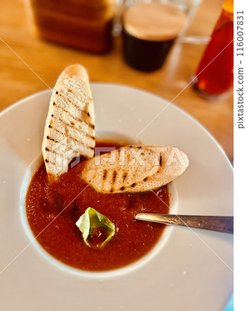 Gazpacho soup with toasted bread on a white plate in a restaurant Gazpacho soup with toasted bread on a white plate in a restaurant 116007831