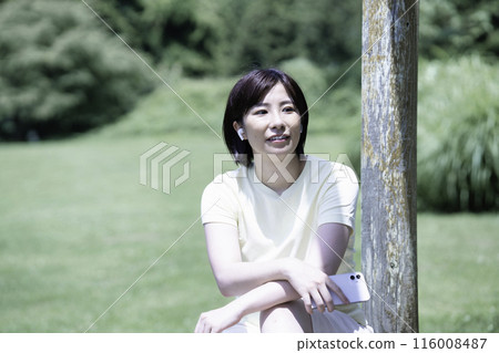 一位女士在新鮮的綠色植物中聽音樂放鬆身心 一位女士在新鮮的綠色植物中聽音樂放鬆身心 116008487