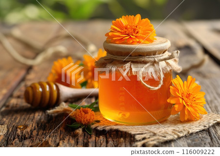 Jar of honey with calendula flowers on wooden table, closeup Jar of honey with calendula flowers on wooden table, closeup 116009222