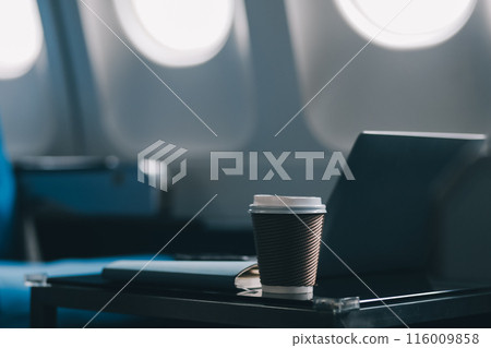 Asian businessman enjoying enjoys a coffee comfortable flight while sitting in the airplane cabin, Passengers near the window. 116009858