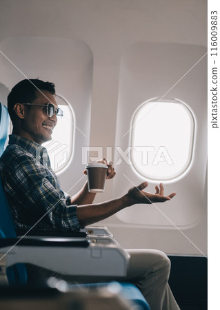 Asian man enjoying enjoys a coffee comfortable flight while sitting in the airplane cabin, Passengers near the window. 116009883