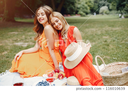 Beautiful girl in a red dress. Women sitting in a summer park. Beautiful girl in a red dress. Women sitting in a summer park. 116010639