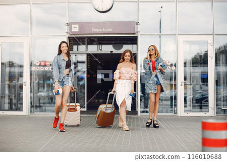 Girls at the airport. Friends with suitcases. Entrace to the airport 116010688