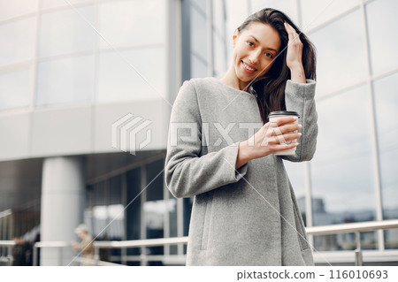 Beautiful girl in a city. Stylish girl near gray building 116010693