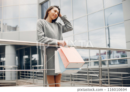 Beautiful girl in a summer city. Lady with shopping bags 116010694