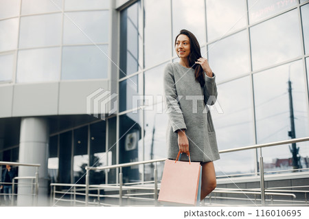 Beautiful girl in a summer city. Lady with shopping bags 116010695