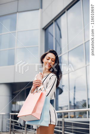 Beautiful girl in a summer city. Lady with shopping bags 116010697