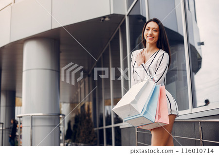 Beautiful girl in a summer city. Lady with shopping bags 116010714