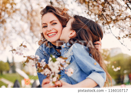 Fashionable mother with daughter. Family in a spring park. Woman in a blue shirt 116010717