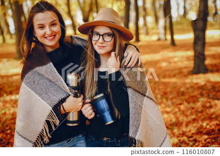 Beautiful girls in a park. Cute ladies in a stylish clothes. Beautiful girls in a park. Cute ladies in a stylish clothes. 116010807