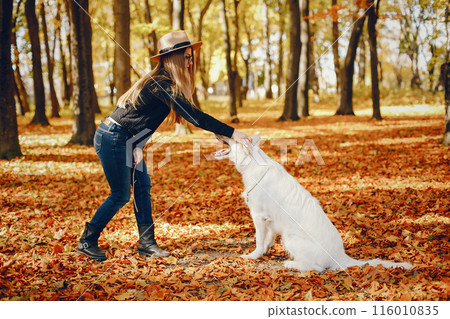 Beautiful girls in a park. Cute ladies in a stylish clothes. Girl with cute dog Beautiful girls in a park. Cute ladies in a stylish clothes. Girl with cute dog 116010835