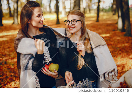 Beautiful girls in a park. Cute ladies in a stylish clothes. Beautiful girls in a park. Cute ladies in a stylish clothes. 116010846