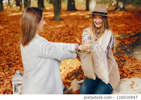 Beautiful girls in a park. Cute ladies in a stylish clothes Beautiful girls in a park. Cute ladies in a stylish clothes 116010847
