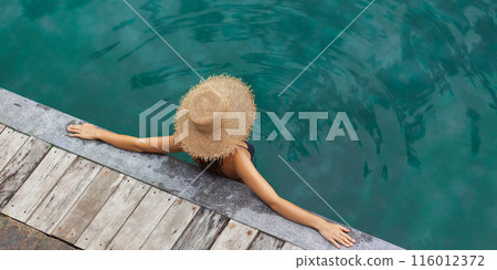 Woman Lounging By Poolside In Straw Hat Captured From Above Woman Lounging By Poolside In Straw Hat Captured From Above 116012372