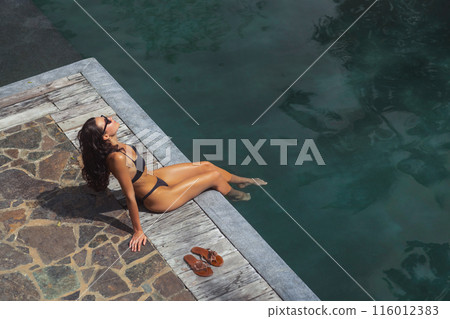 Woman Sunbathing by Poolside with Sandals Woman Sunbathing by Poolside with Sandals 116012383