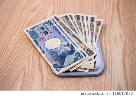 Japanese 1,000 and 10,000 yen bills are placed in change trays for businesses and purchases. 116013030