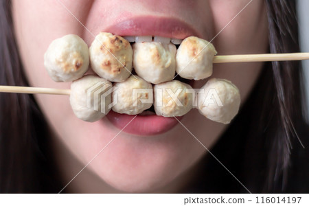 Woman happily eating meatball on blurred background Woman happily eating meatball on blurred background 116014197