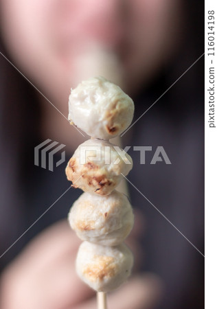 Woman happily eating meatball on blurred background 116014198