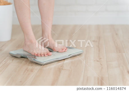 The feet of a woman standing on a weight scale, body composition scale, and body fat scale 116014874