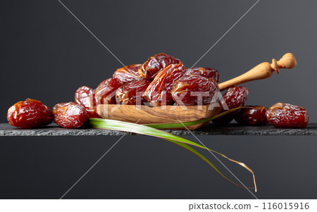 Closeup sweet dried dates in wooden dish. Closeup sweet dried dates in wooden dish. 116015916