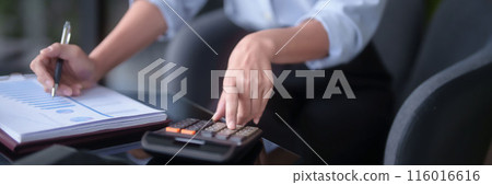 Asian businesswomen using calculator to calculating financial statistics data and checking marketing business document while analyze investment and market stock of new startup in outside office 116016616