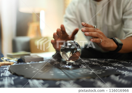 Mysterious fortune teller predicting future with crystal ball on desk. Astrologists, forecasting and divination concept Mysterious fortune teller predicting future with crystal ball on desk. Astrologists, forecasting and divination concept 116016966