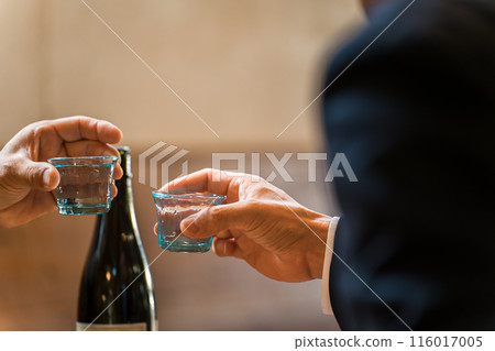 The hands of an office worker toasting with a sake cup at an izakaya or bar The hands of an office worker toasting with a sake cup at an izakaya or bar 116017005